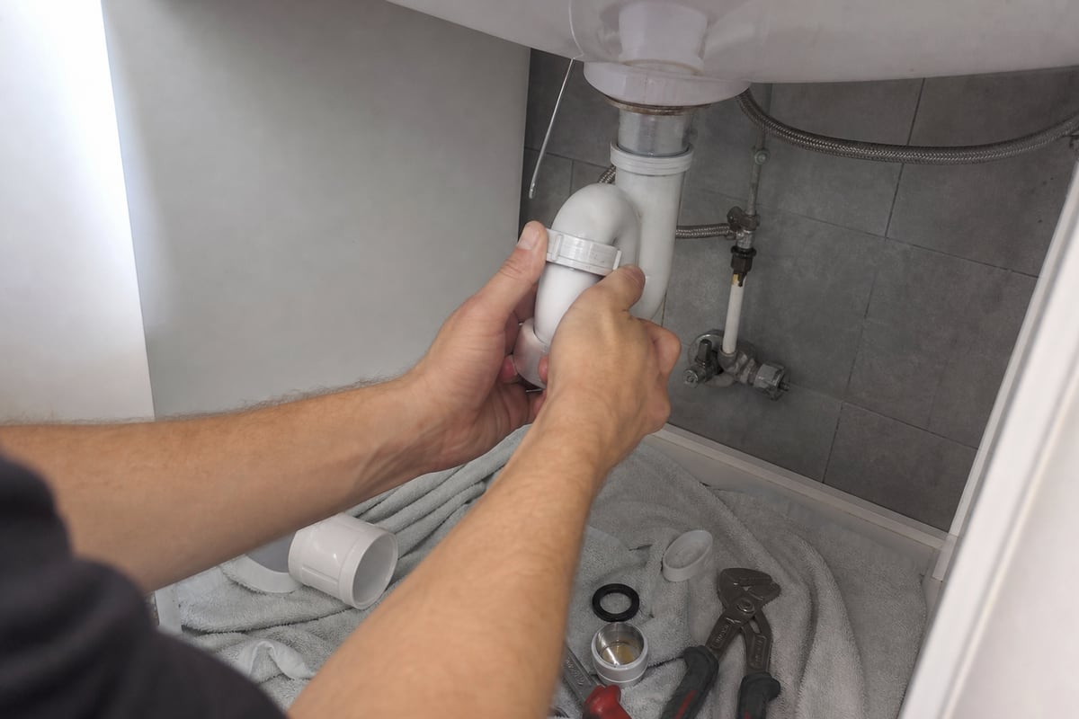 mains dévissent tuyau évacuation sous lavabo