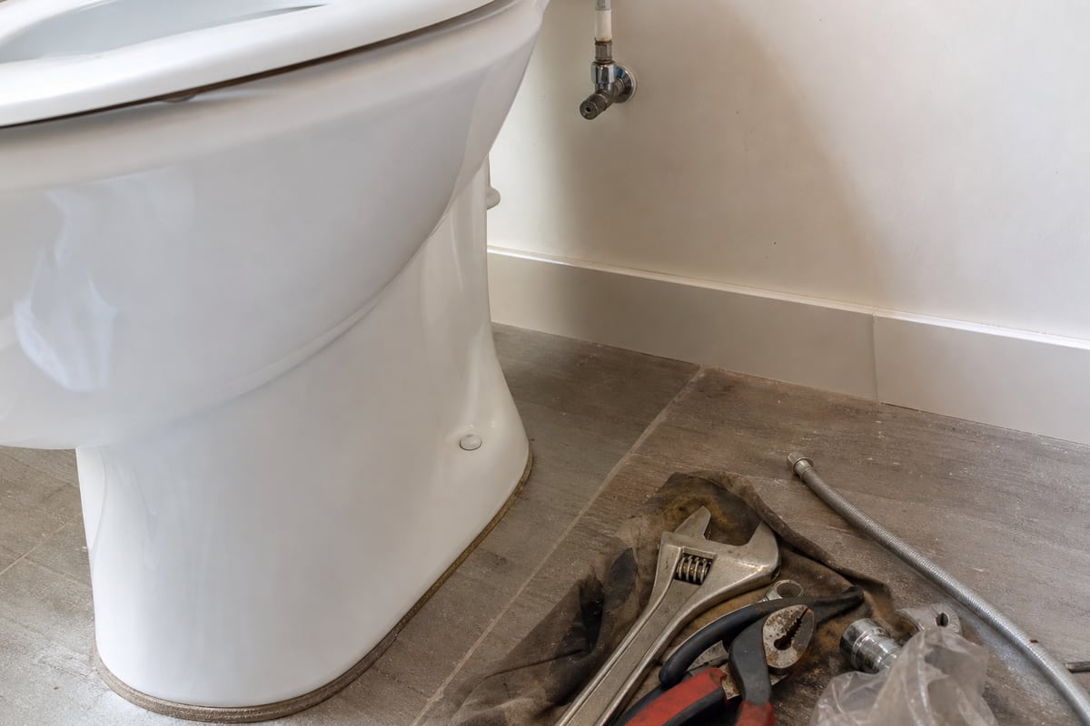 outillage de plombier posé près d'une cuvette de WC